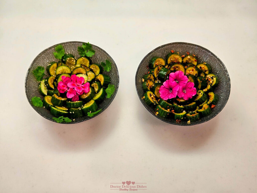 Two bowls of Chinese Cucumber Salad garnished with pink flowers and cilantro, presented side by side, with one spicy and one non-spicy version, showcasing vibrant and fresh ingredients.