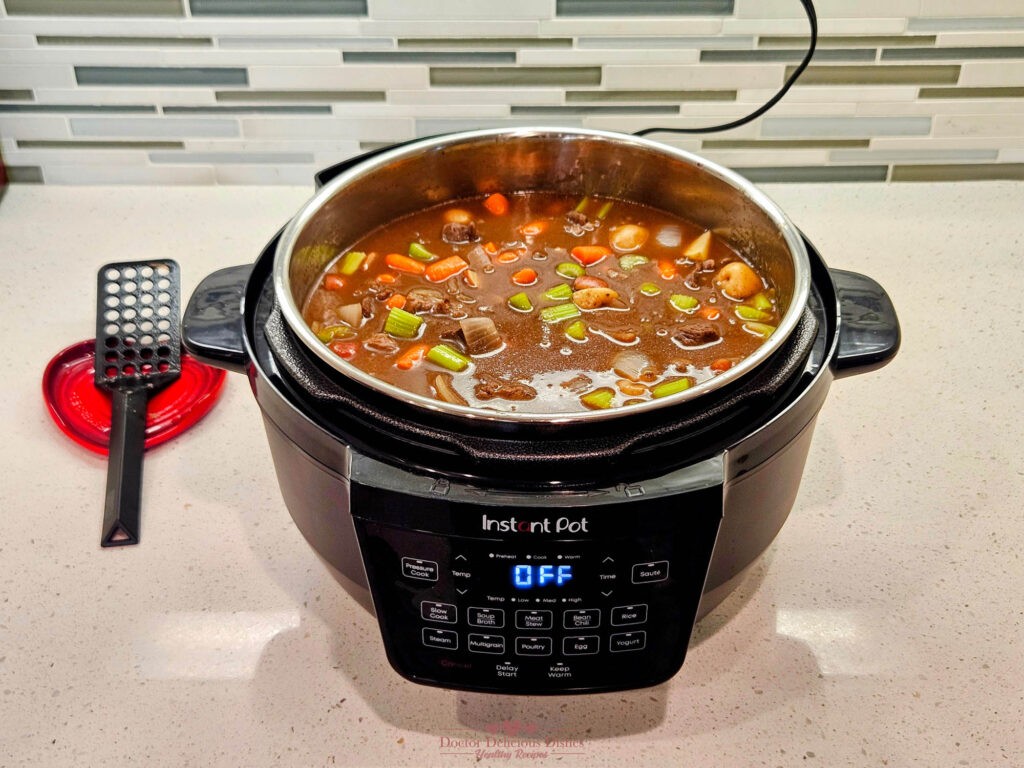 Beef stew fully cooked in the Instant Pot, with vegetables soft and broth thickened.