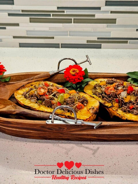 The final dish, two roasted spaghetti squash halves filled with the ground beef mixture, presented in a rustic wooden serving bowl, garnished with vibrant red flowers, giving a fresh, colorful presentation of the dish.