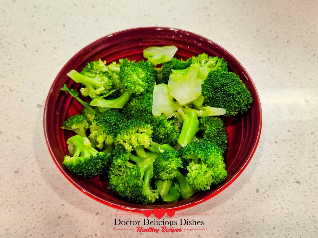 Blanched broccoli in a red bowl for Chinese Beef and Broccoli Recipe.