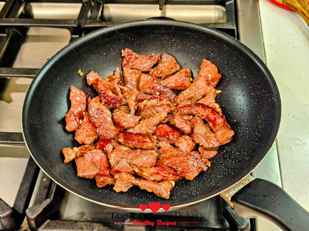 Sizzling beef in a skillet, seared for Chinese Beef and Broccoli Recipe.