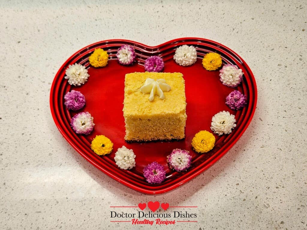 Serving the homemade cornbread on a heart shaped plate with a flower shaped dollop of butter melting on top and several flowers decorating the edge of the plate.