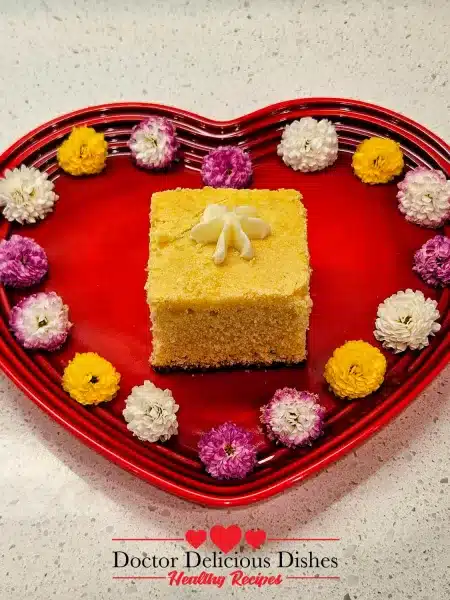 Serving the homemade cornbread on a heart shaped plate with a flower shaped dollop of butter melting on top and several flowers decorating the edge of the plate.