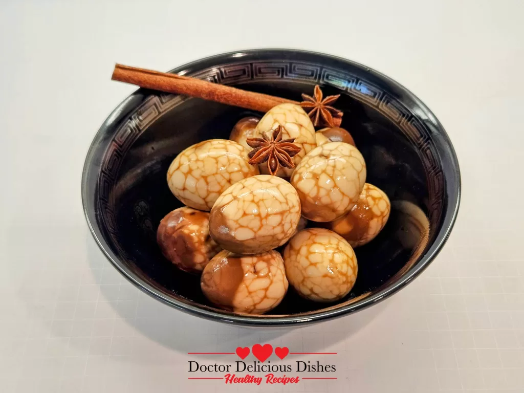 Finished tea eggs in a bowl garnished with cinnamon stick and star anise.