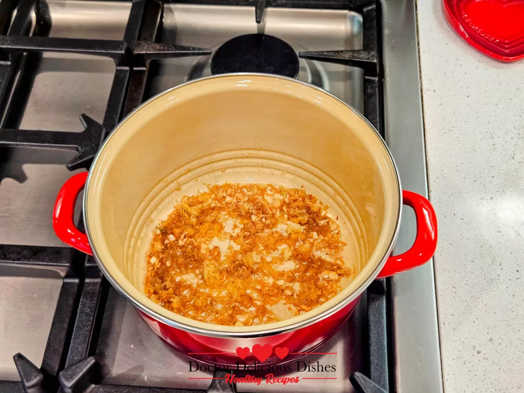 A sautéed mix of garlic and butter in the bottom of a mussel pot, ready for deglazing with white wine.