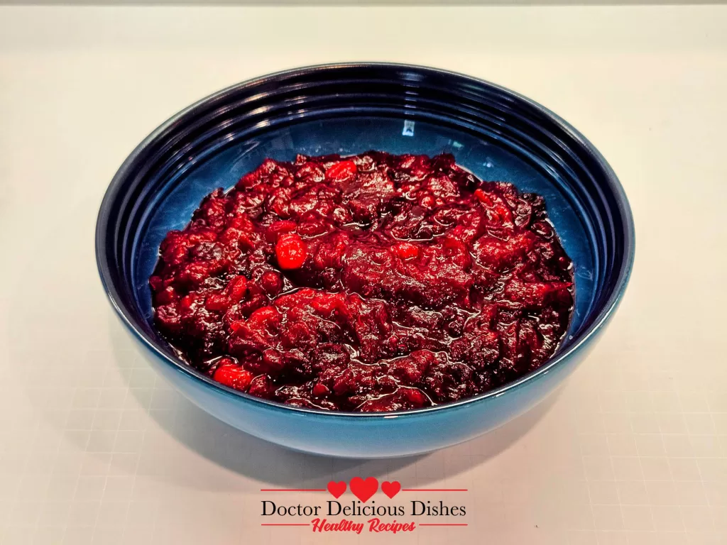 A blue Le Creuset bowl filled with finished cranberry sauce, ready to serve at the holiday table.