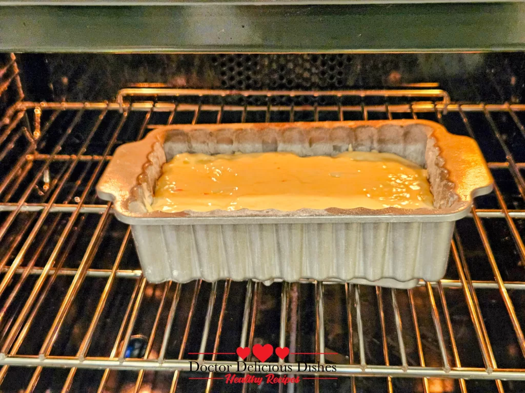 A loaf pan filled with creamy cake batter placed in the center of a preheated oven, beginning the baking process.