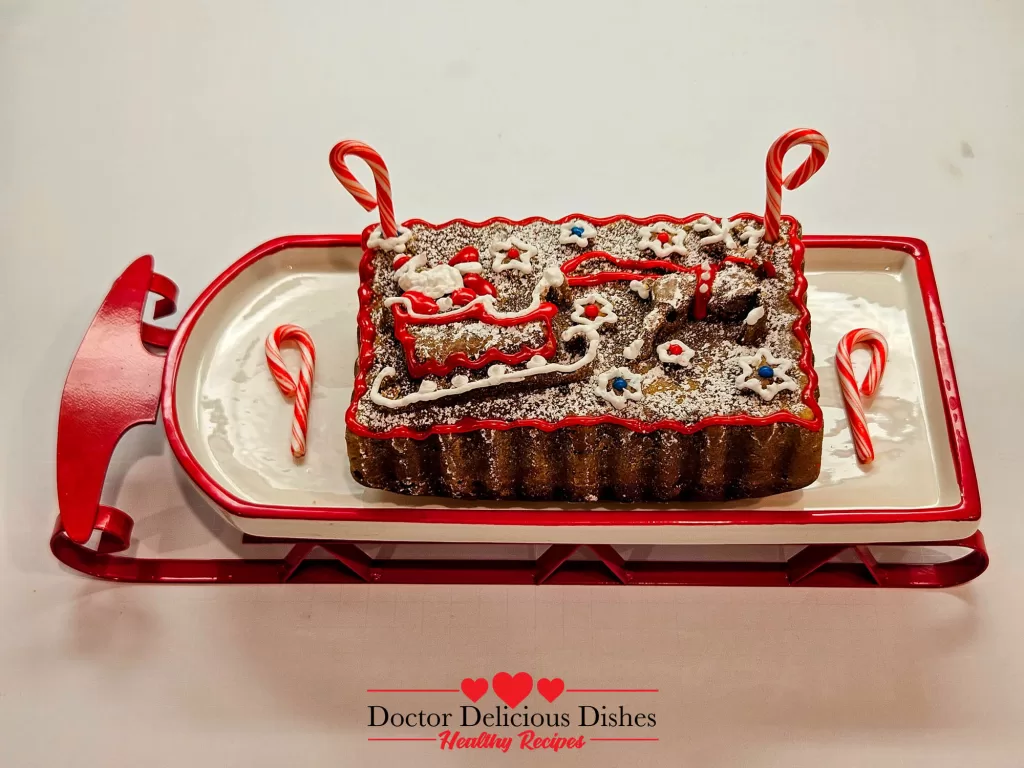 A rectangular peppermint cake, dusted with powdered sugar and decorated with red and white icing and candy canes, presented on a festive sled-shaped platter.