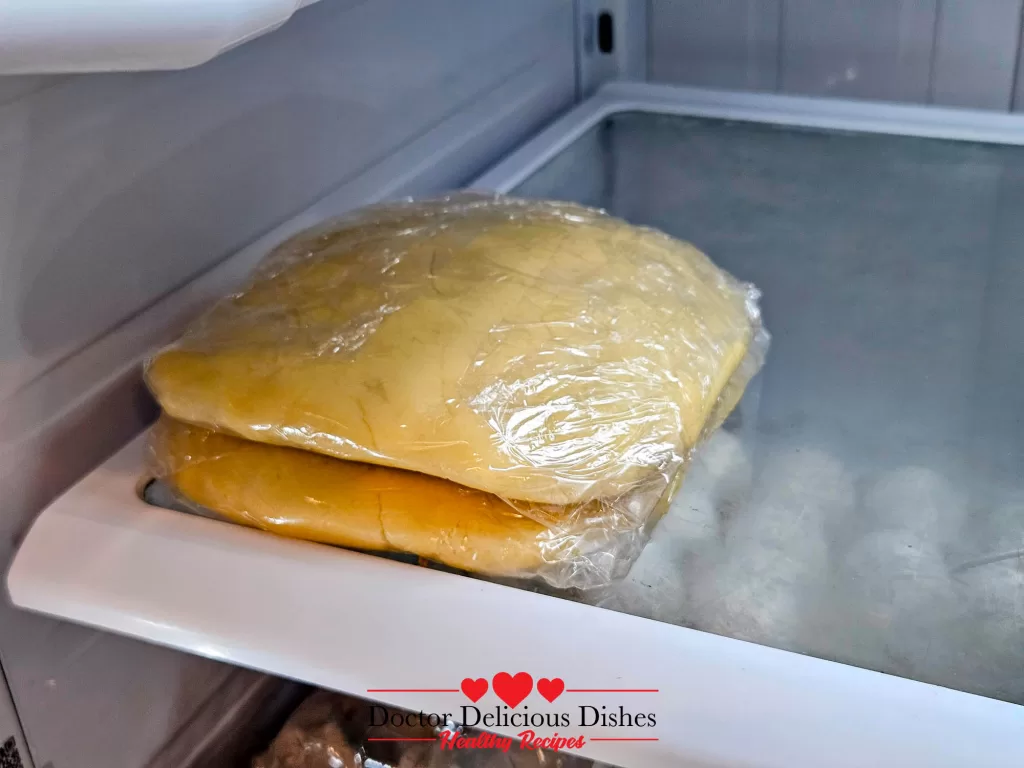 Two disks of wrapped cookie dough stacked and chilling in the refrigerator.