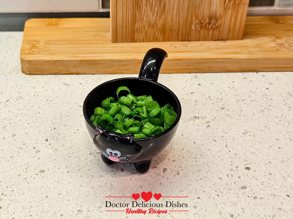 Finely chopped green onions in a playful, black cat-shaped bowl.