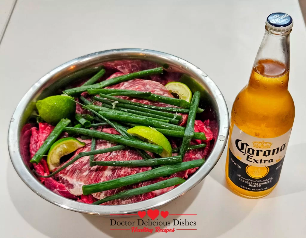 Bowl with skirt steak, lime wedges, green onions, and Corona Light beer for air fryer skirt steak marinade.