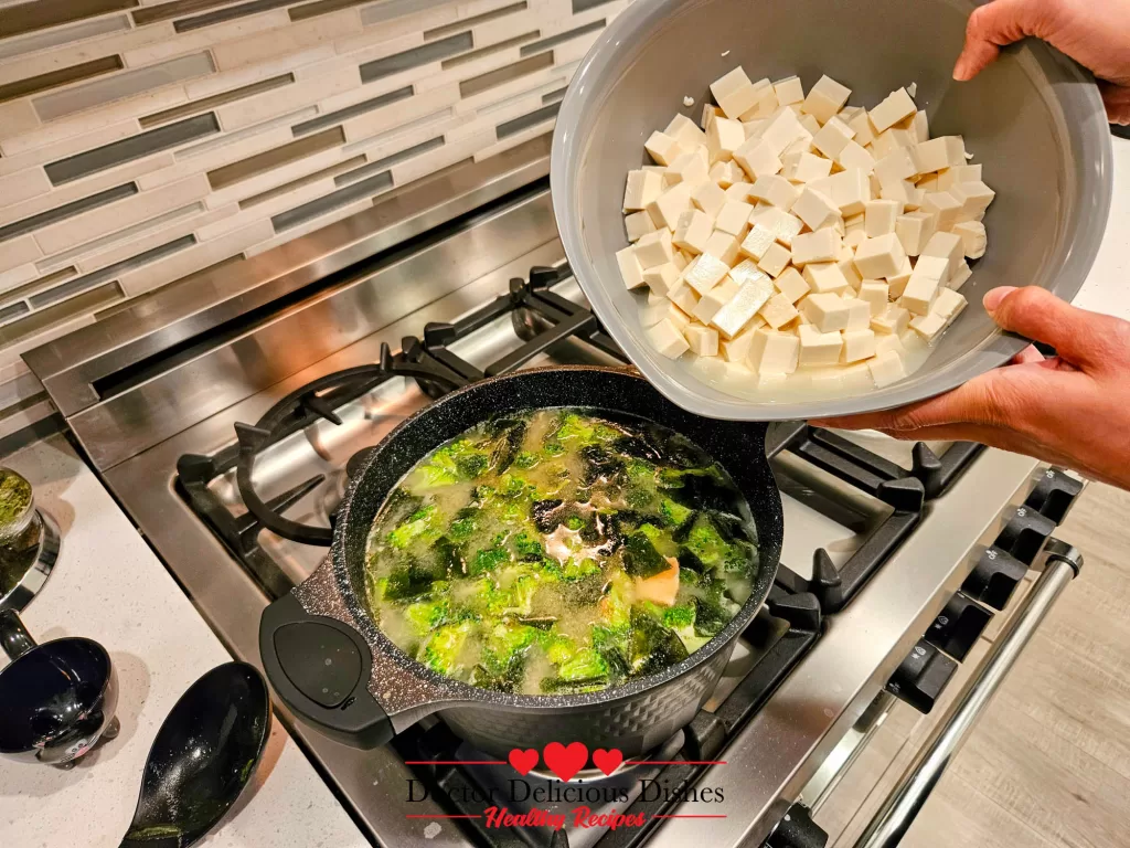 The fifth image shows cubed tofu being added to the bubbling pot of Savory Salmon Tofu Miso Soup with Broccoli.