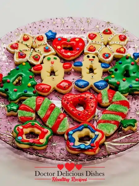 A platter of decorated Easy Frosted Sugar Cookies, featuring festive designs with icing and sprinkles ready for Christmas.