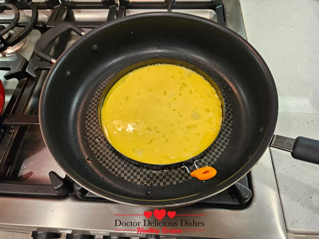 A frying pan with a circular omelet cooking inside an omelet ring, adding the finishing touch to this Japanese Chicken Curry Recipe.