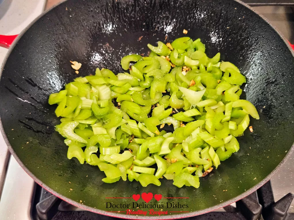 – Freshly sliced celery cooking in the wok with sautéed garlic and ginger, beginning to soften and release its natural sweetness.