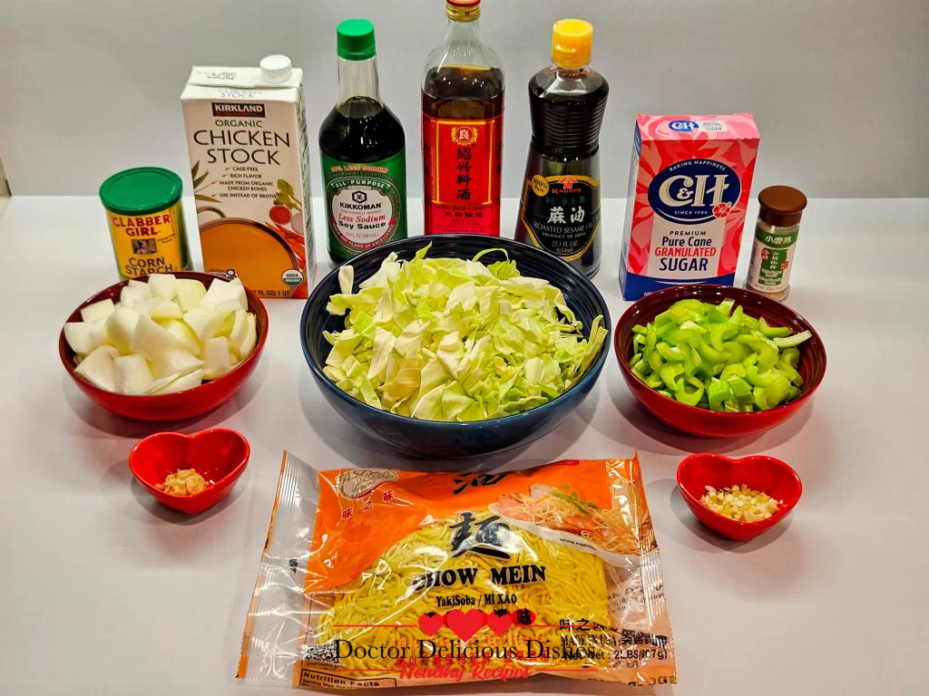 Ingredients for Copycat Panda Express Chow Mein Noodles laid out on a white surface, including fresh chow mein noodles, cabbage, onions, celery, garlic, ginger, soy sauce, chicken stock, sesame oil, Shaoxing wine, cornstarch, white pepper, and sugar.