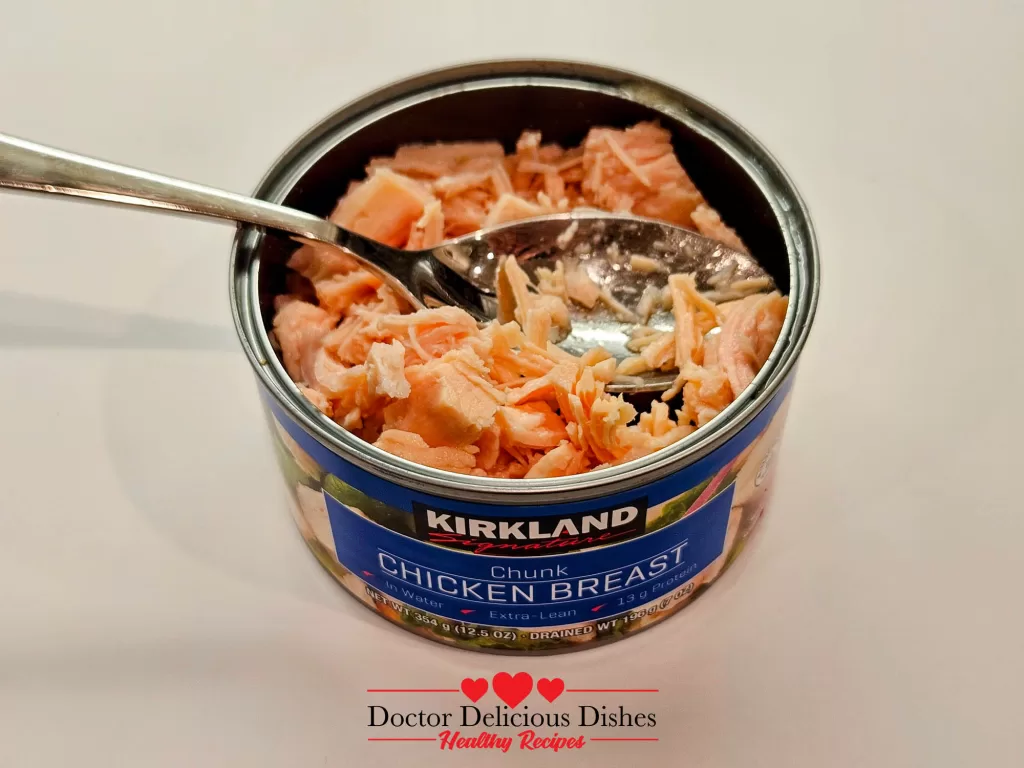 Close-up of flaked canned chicken breast in its opened can, ready to be added to Homemade Chicken Noodle Soup with Egg Noodles.