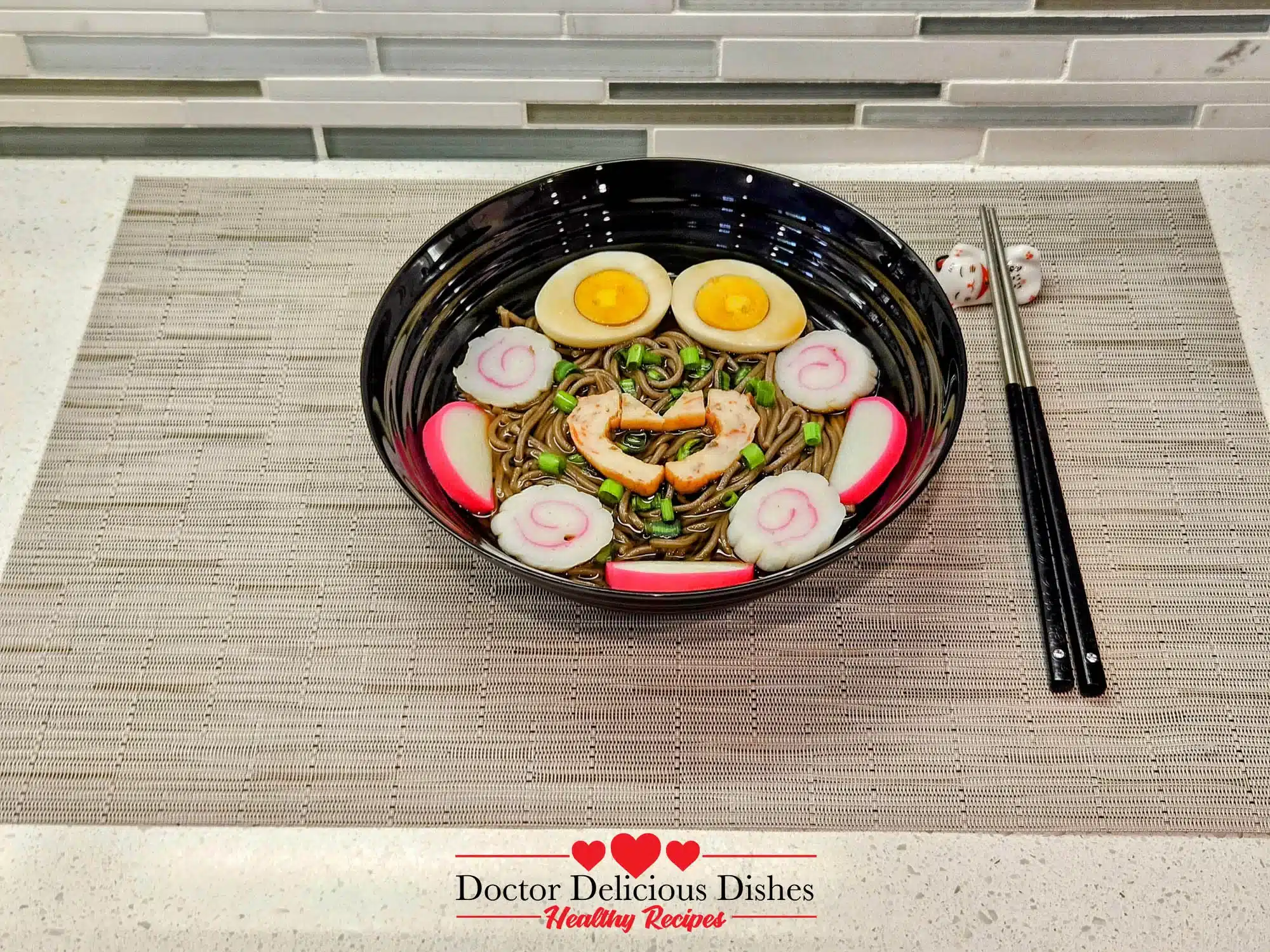 Side view of a bowl of hot soba noodle soup with traditional toppings, paired with chopsticks.