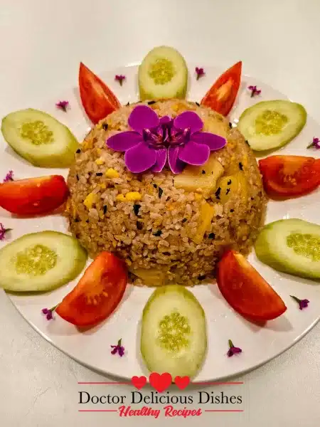 Thai Pineapple Fried Rice beautifully presented with cucumber and tomato slices, garnished with fresh basil and an edible flower.