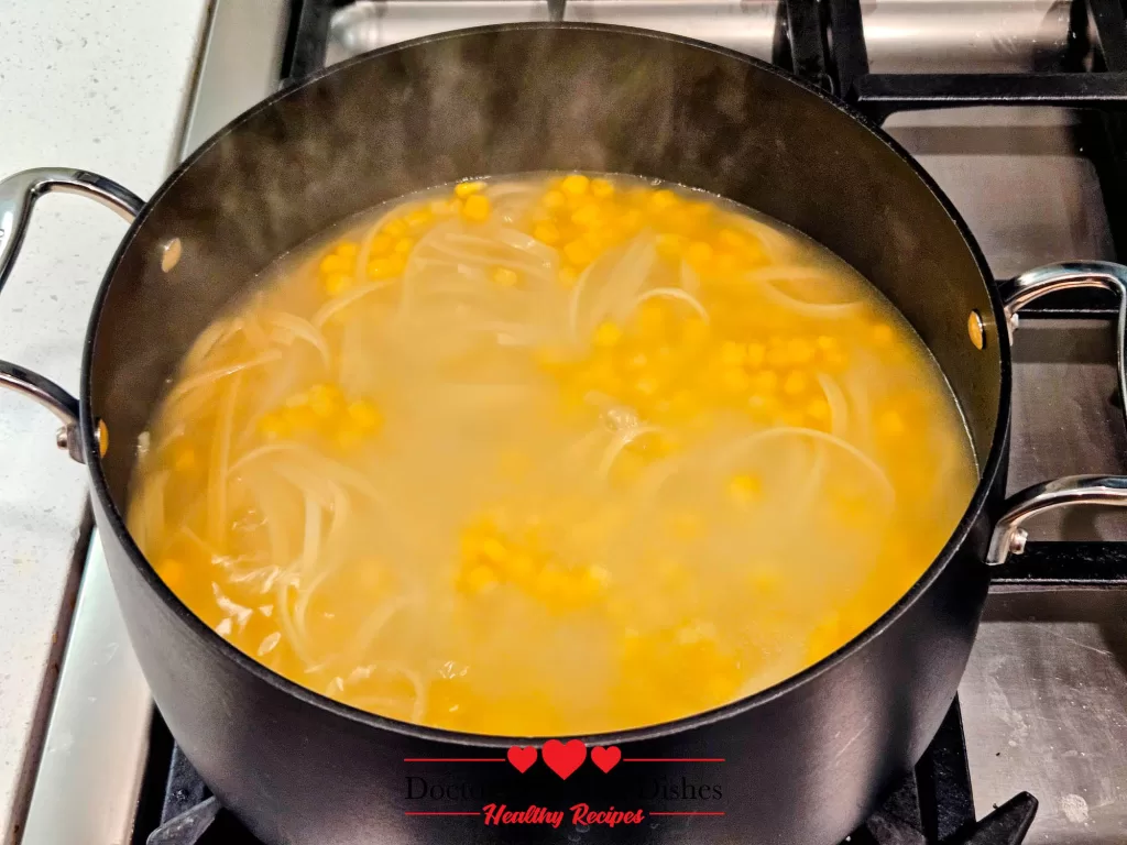 Pasta and sweet corn kernels bubbling together in the pot for a Chicken Alfredo Recipe with Jar Sauce.