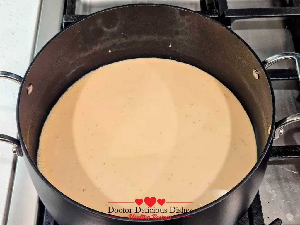 A pot of creamy jar Alfredo sauce gently warming on the stovetop for a Chicken Alfredo Recipe with Jar Sauce.