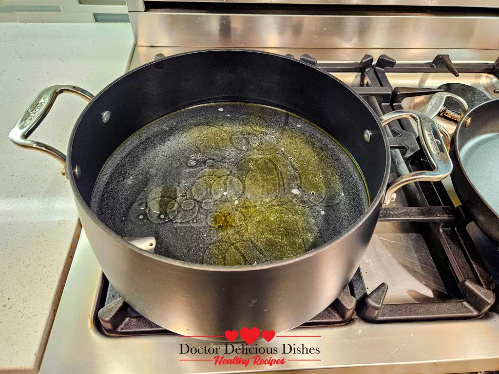 A large pot on the stovetop filled with water and a swirl of oil, ready to boil pasta for a Chicken Alfredo Recipe with Jar Sauce.