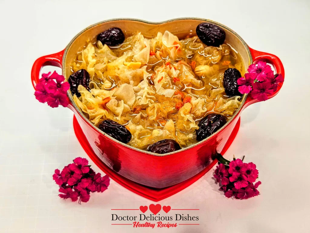 A beautifully simmered Easy Tong Sui Recipe served in a red heart-shaped Le Creuset pot, garnished with pink flowers for an elegant presentation.