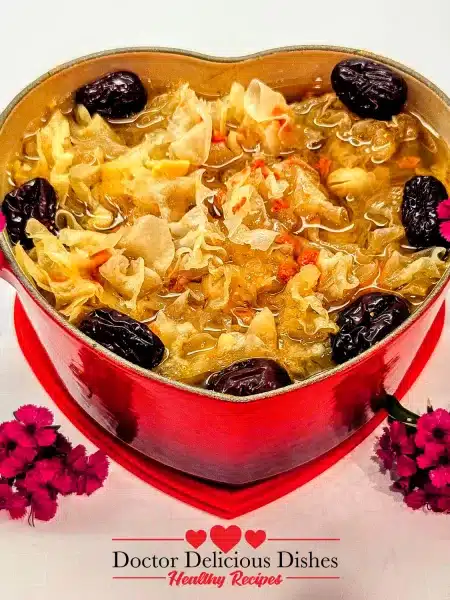 A beautifully simmered Easy Tong Sui Recipe served in a red heart-shaped Le Creuset pot, garnished with pink flowers for an elegant presentation.