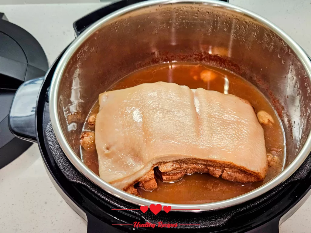 Tender cooked pork belly resting in the Instant Pot after pressure cooking in a flavorful marinade.