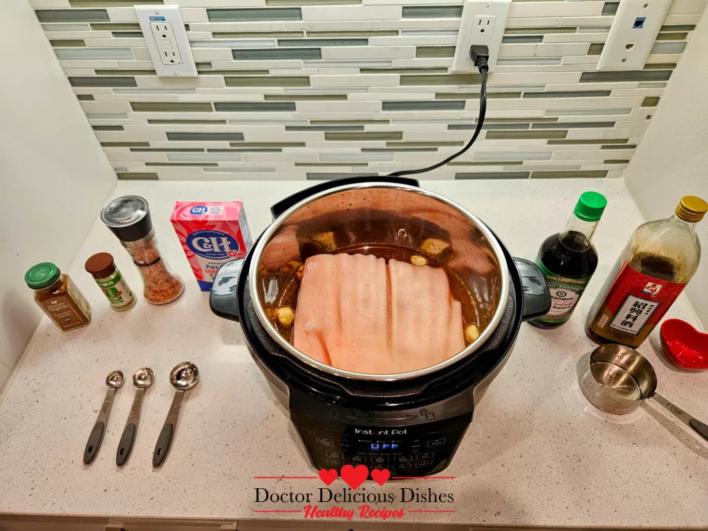 Raw pork belly placed in the Instant Pot, submerged in the marinade for cooking.