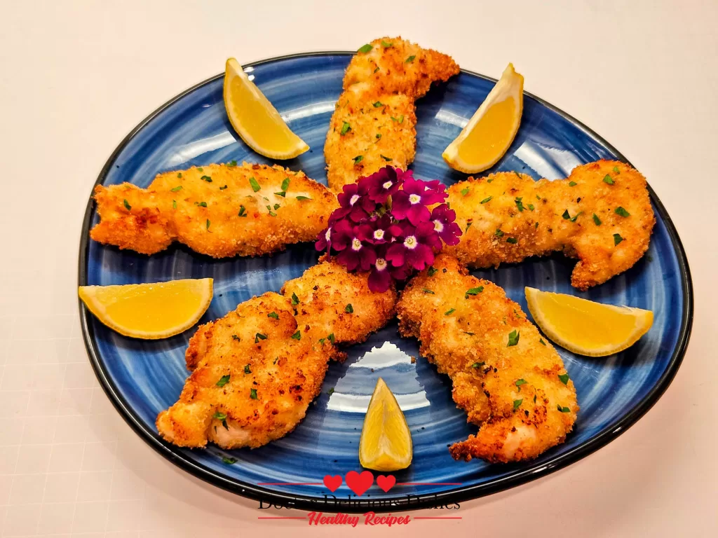 Crispy Air Fryer Chicken Tenders beautifully plated on a blue dish with lemon wedges and garnished with fresh parsley.