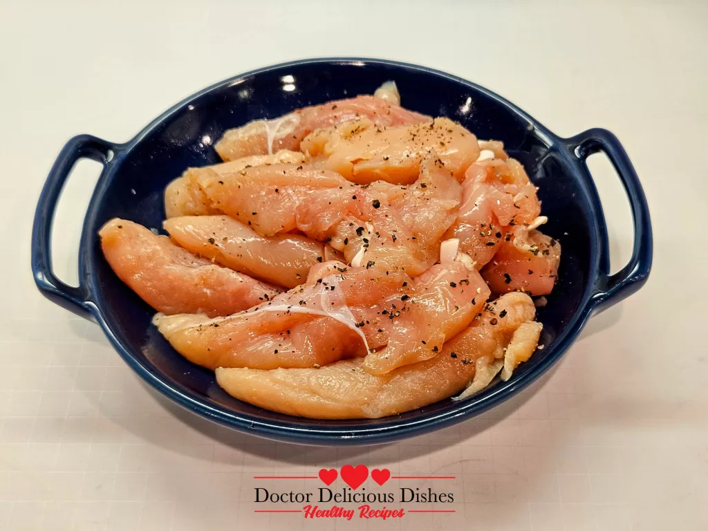 Seasoned raw chicken tenders in a blue dish, ready to be breaded for Crispy Air Fryer Chicken Tenders.