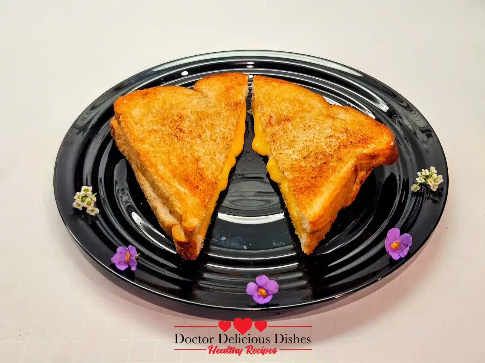 Air fryer grilled cheese plated with small purple and white blossoms.
