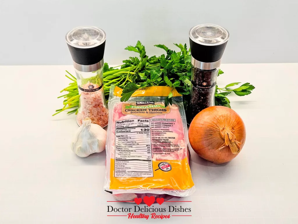 Ingredients for Instant Pot Chicken Thighs laid out, including garlic, onion, parsley, salt, pepper, and packaged boneless skinless chicken thighs