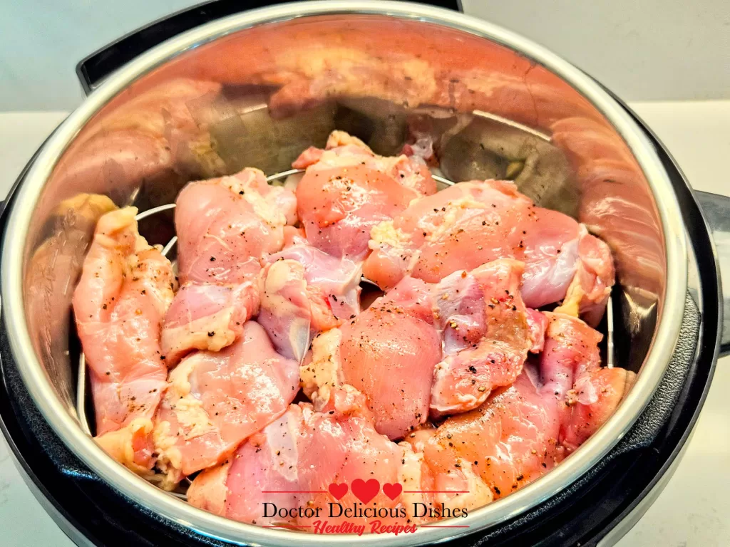 Seasoned chicken thighs arranged on a trivet inside the Instant Pot