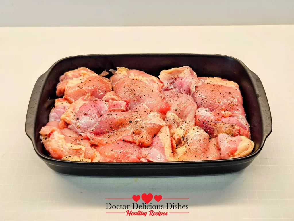 Chicken thighs seasoned with salt and pepper arranged in a black dish