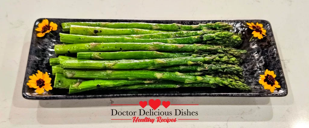 Cooked Air Fryer Asparagus plated on a black floral dish, ready to eat.