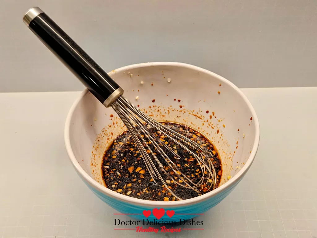 Whisking homemade teriyaki sauce in a bowl for air fryer pork chops