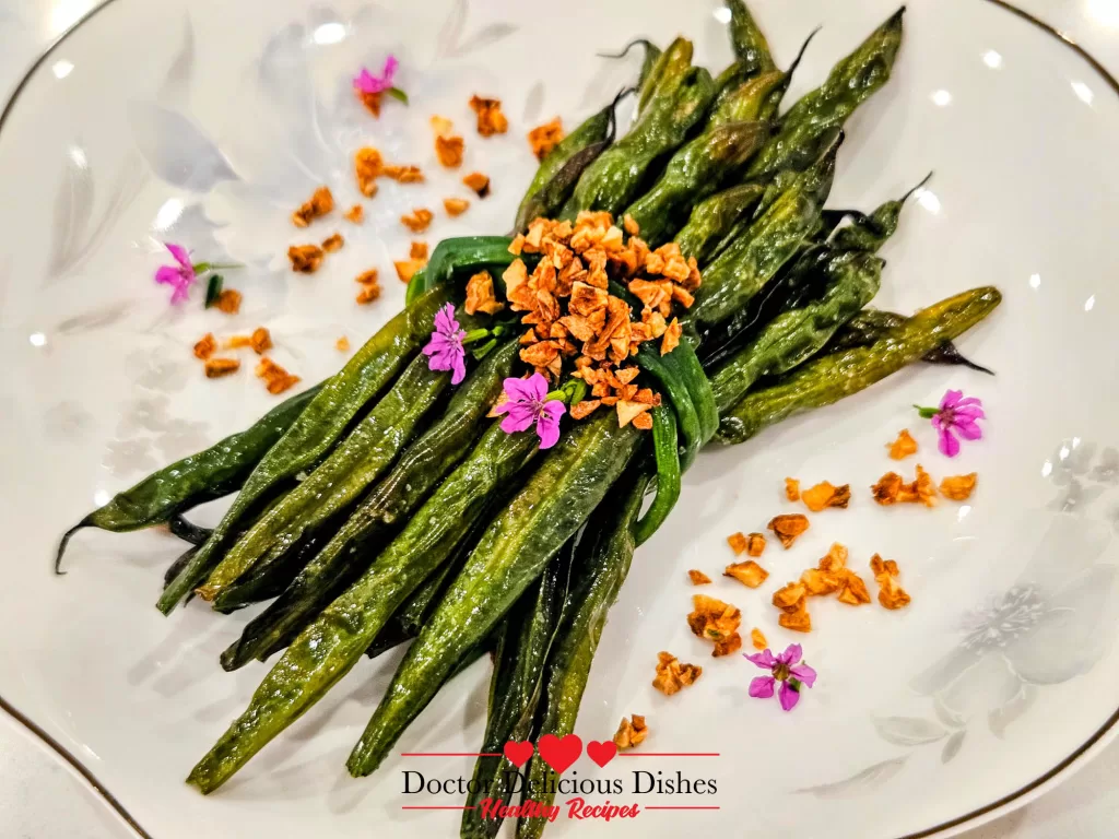 Close-up of Air Fryer Green Beans with crispy garlic bits and floral garnish