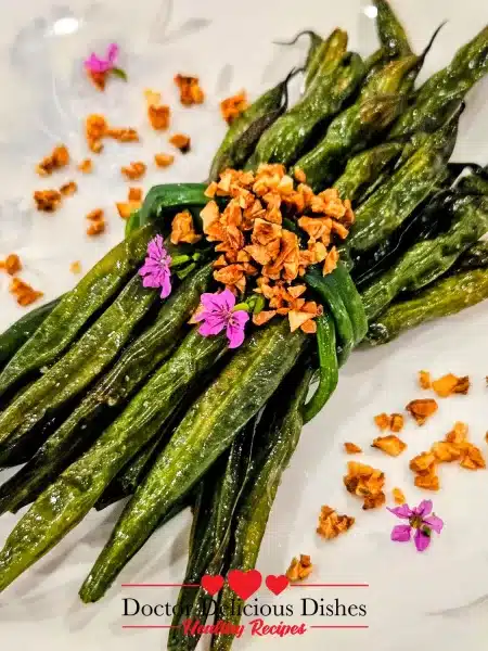 Close-up of Air Fryer Green Beans with crispy garlic bits and floral garnish