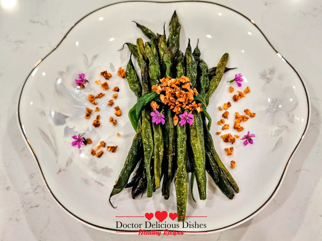 Air Fryer Green Beans plated with crispy garlic and edible flowers for a beautiful presentation