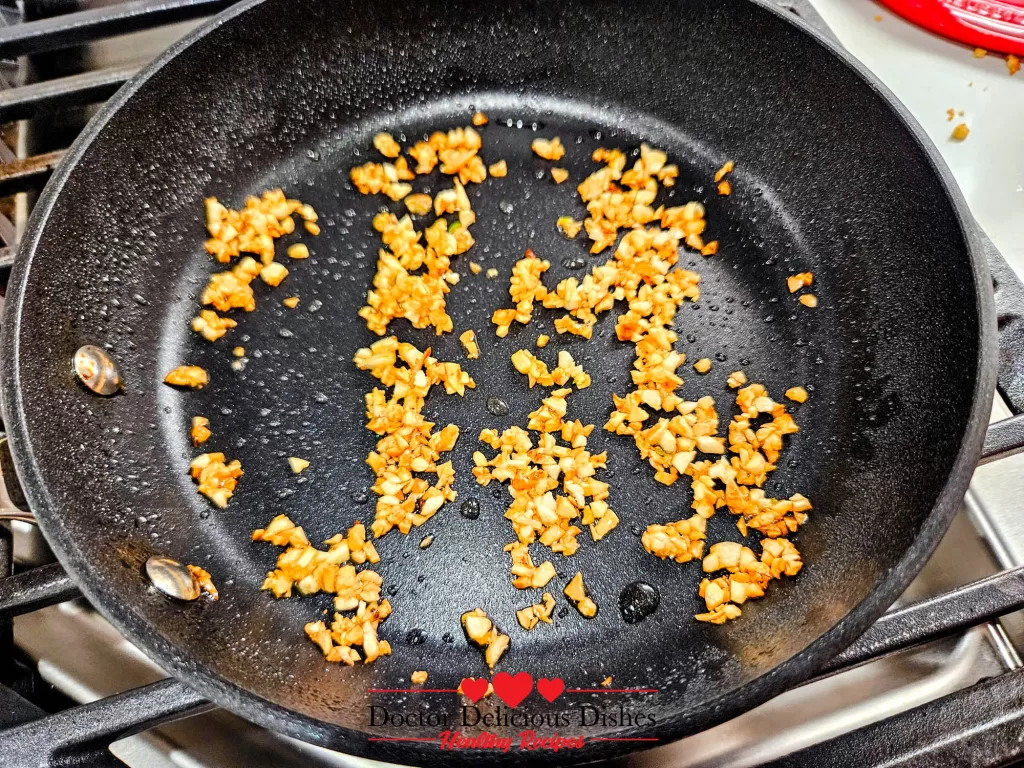 Chopped garlic sautéing in a pan to top the Air Fryer Green Beans