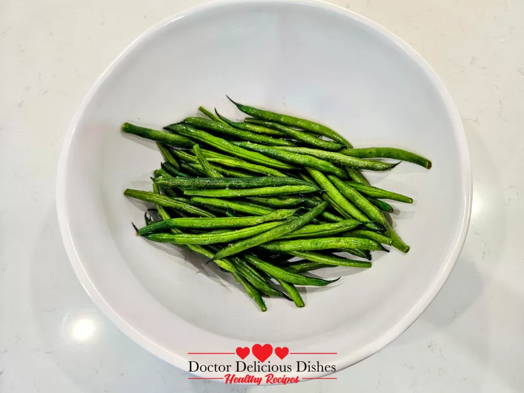 Green beans tossed with avocado oil in a white bowl for Air Fryer Green Beans recipe