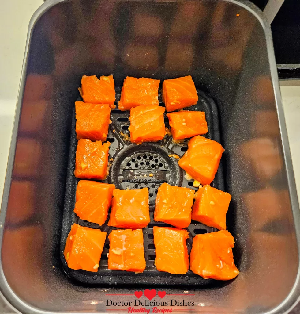 Salmon bites placed in air fryer basket ready to cook.