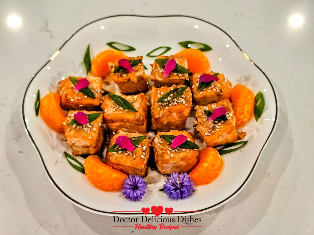 Air Fryer Salmon Bites garnished with green onions, sesame seeds, and mandarin slices
