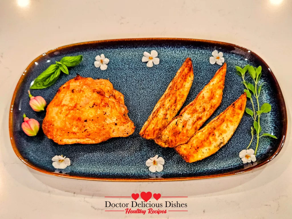 Air Fryer Chicken Thighs served with crispy potato wedges and floral garnish on a blue dish.