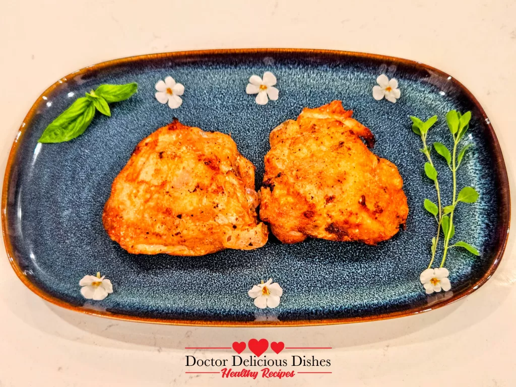 Final plated Air Fryer Chicken Thighs on a blue flower dish, garnished with fresh herbs.