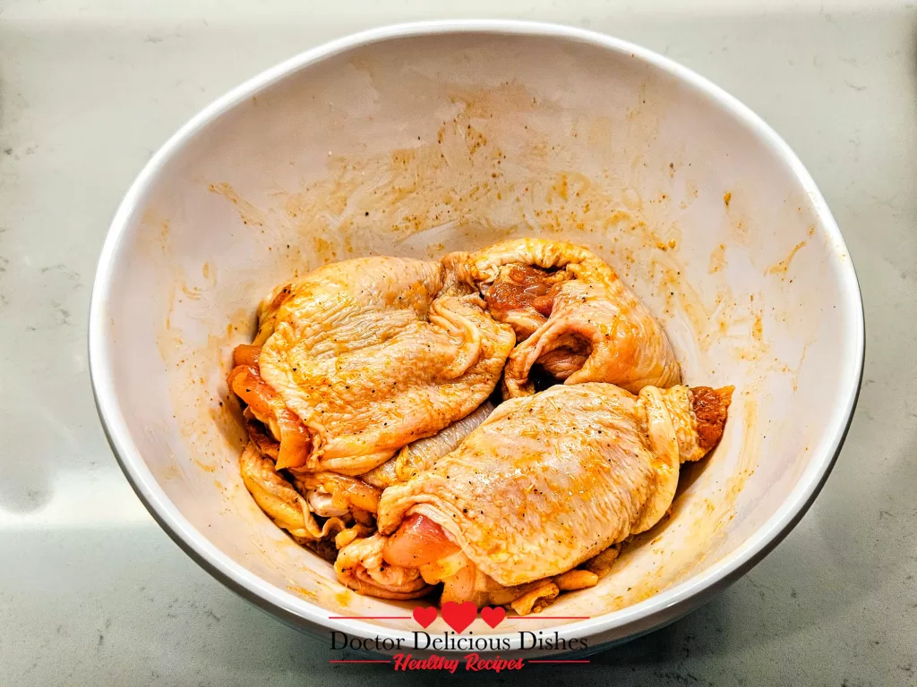 Raw chicken thighs seasoned with Kinder’s The Blend in a white bowl, ready to cook for Air Fryer Chicken Thighs.