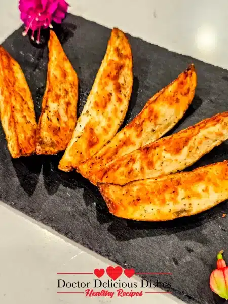 Crispy Air Fryer Potato Wedges plated on a slate board, fanned out next to decorative flowers.