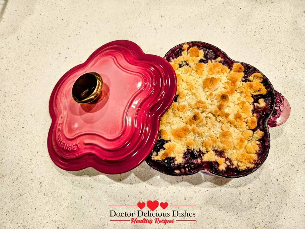 Apple blueberry crumble recipe served in a pink Le Creuset dish with lid.